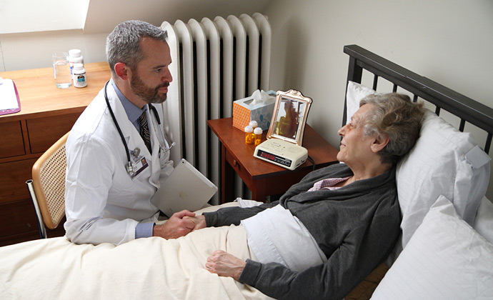 A physician talks to a patient at her bedside