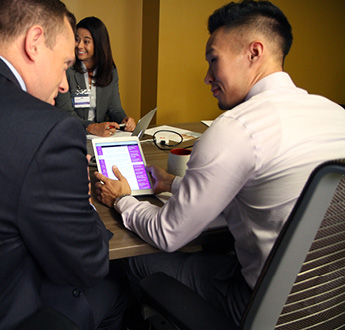 Several healthcare professionals sit at a conference table and look at a tablet