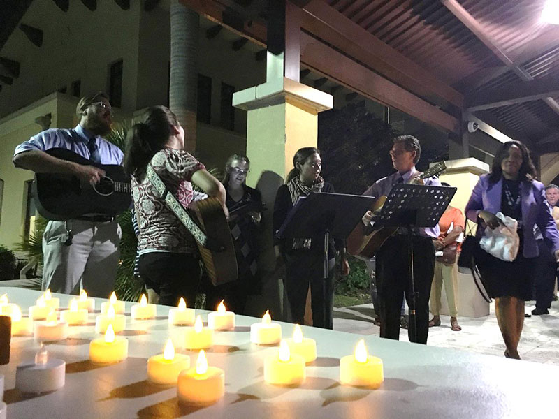 Five music therapists play guitar and sing, with candles in the foreground