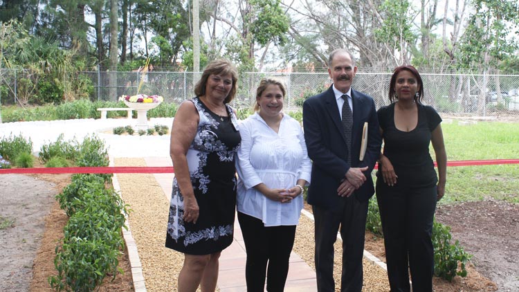 The group poses in front of the ceremonial ribbon at the scatter garden