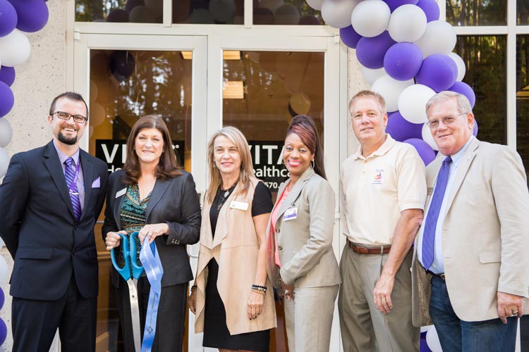 The group posing with the ceremonial scissors and ribbon from the ribbon-cutting