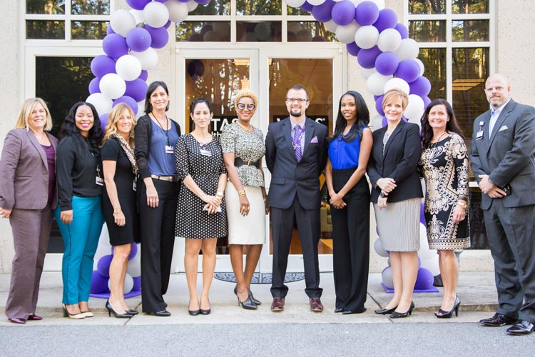 The group standing in front of a balloon arch over the main entrance