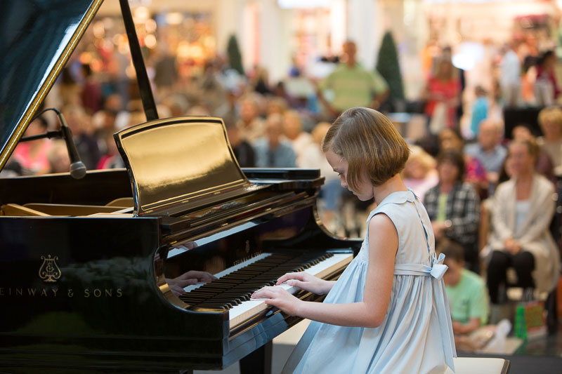 A young girl plays piano