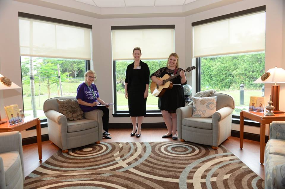 A VITAS music therapy volunteer plays guitar in a public gathering area