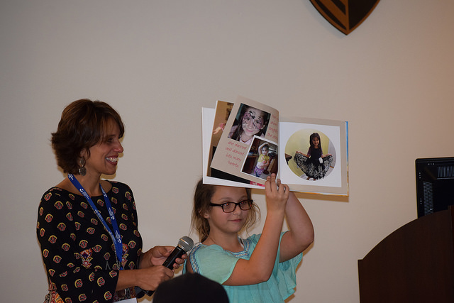 A girl holds up a memory book with photos for the group to see