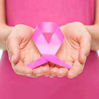 A woman holds a pink ribbon for breast cancer awareness