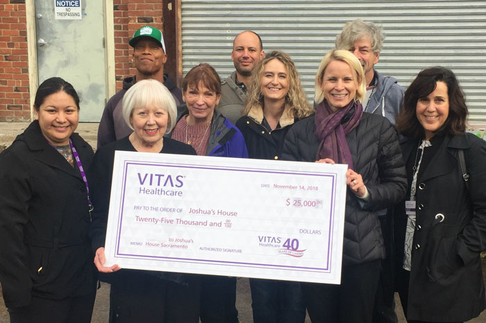 The group holds the oversized check outside Joshua's House