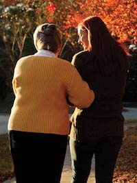 A patient walks arm-in-arm and talks with a chaplain