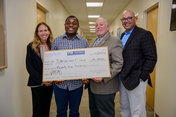 Stevenson Chery holds up a scholarship check