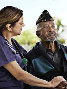 A VITAS team member holds the hand of a United States veteran