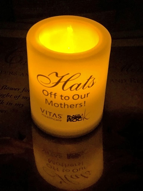 A glowing candle at the Hats Off to Our Mothers event