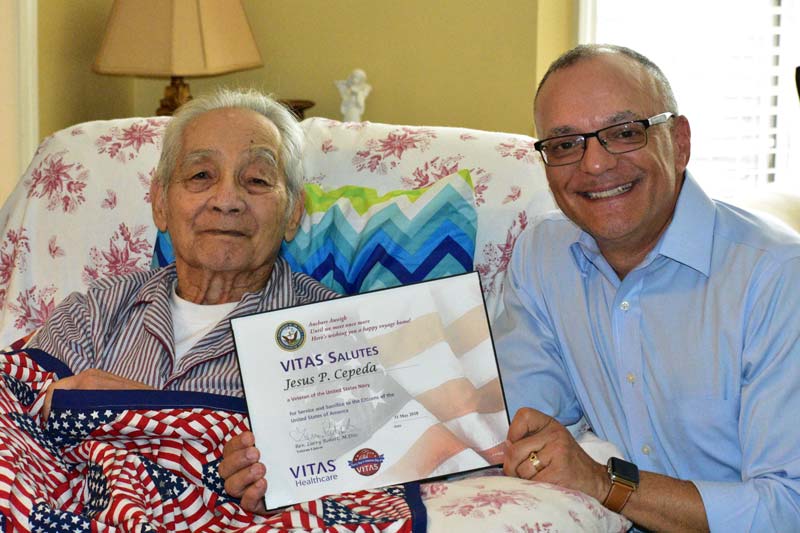 Reverend Larry Robert, bereavement services manager and veteran liaison for VITAS Healthcare in Atlanta, presents Jesus Cepeda with a certificate honoring his service and sacrifice as a U.S. Navy veteran