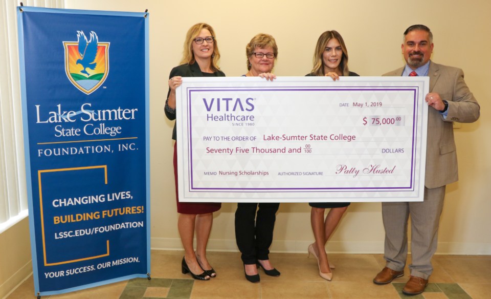 The group holds a large ceremonial check