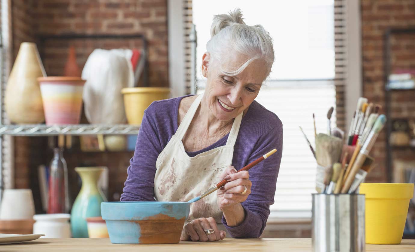 A woman paints a shallow clay pot in an art studio