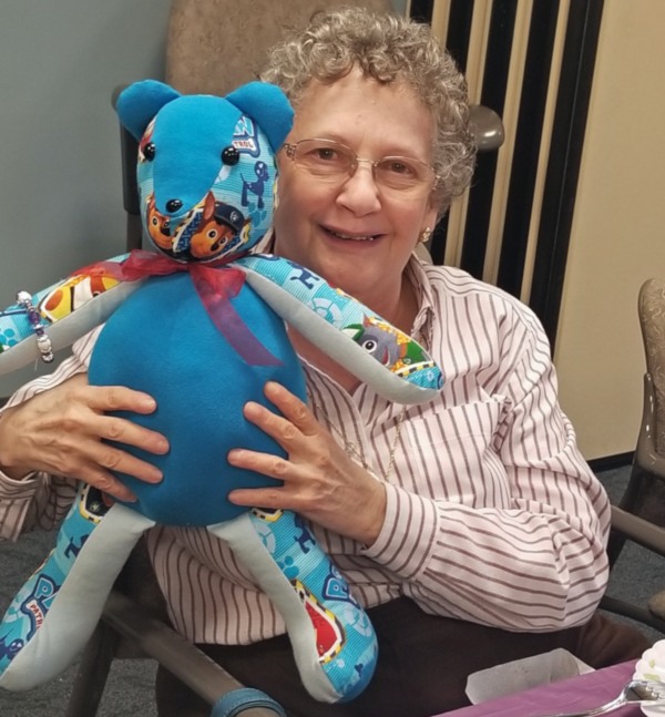 Một người phụ nữ ôm một Chú gấu kỷ niệm do các tình nguyện viên VITAS khâu