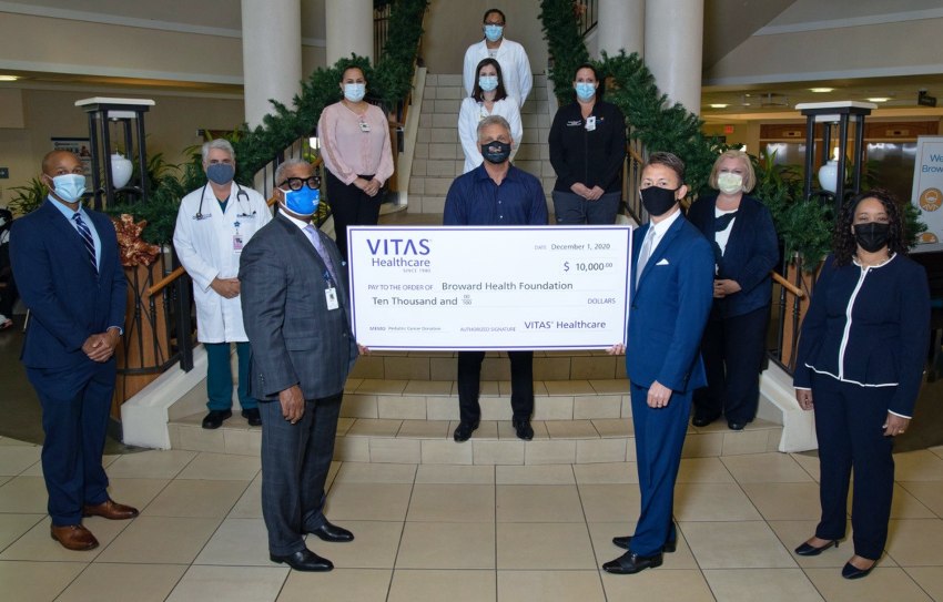 The group poses with a ceremonial check on an atrium stairway