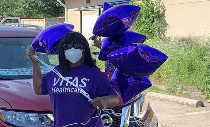 VITAS team member holds five star-shaped purple balloons