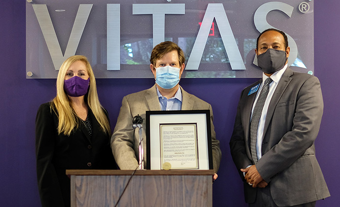 The group stands in front of the VITAS sign with the proclamation