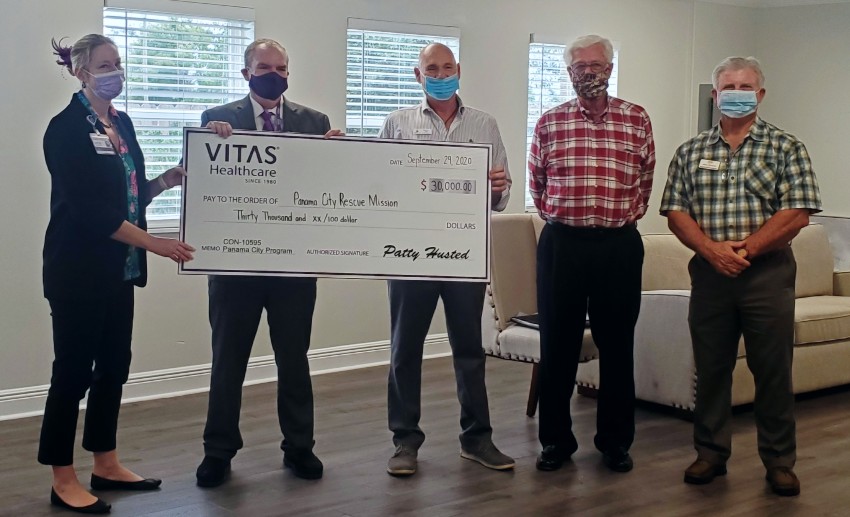 The group poses with a large, ceremonial check