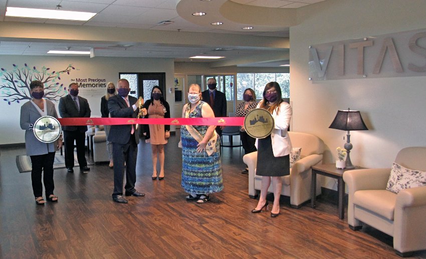 The group holds a ceremonial ribbon for the ribbon-cutting inside the inpatient hospice unit