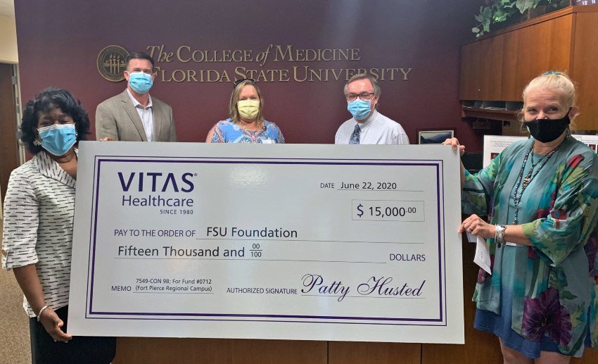 The group holds a large ceremonial check at the FSU College of Medicine offices