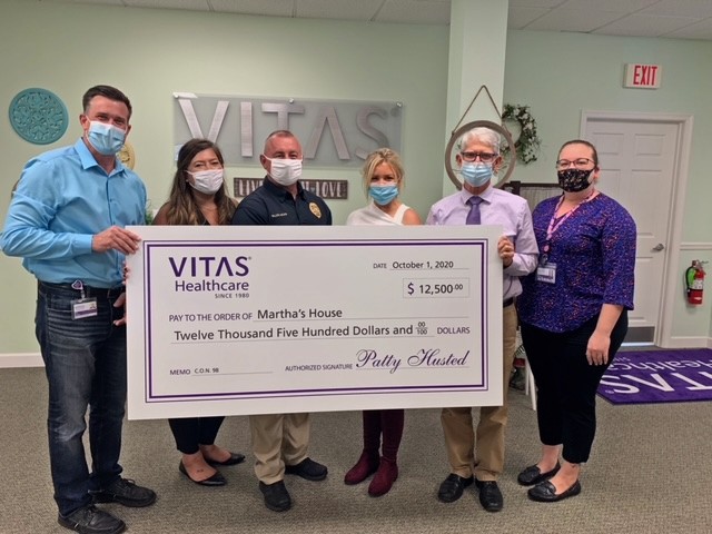 The group poses with a large, ceremonial check