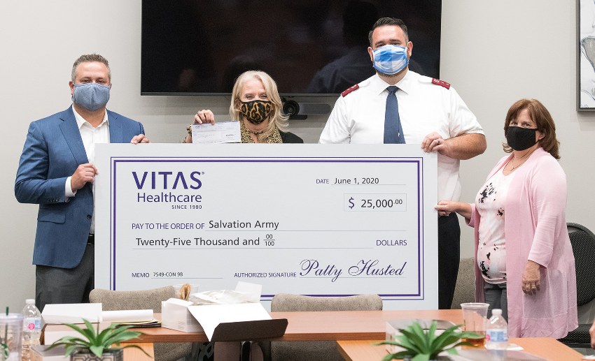 The group holds up a large ceremonial check