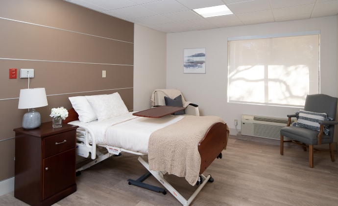 A patient room with a bed and visitor accommodations