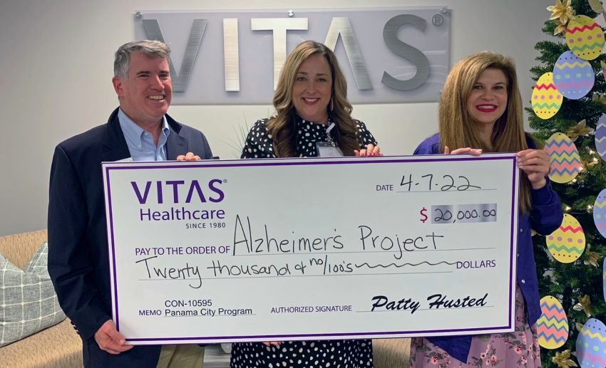 The group holds an oversized ceremonial check inside the VITAS office