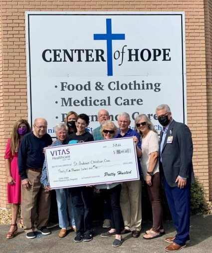 A group stands beneath the Center of Hope sign holding a ceremonial check