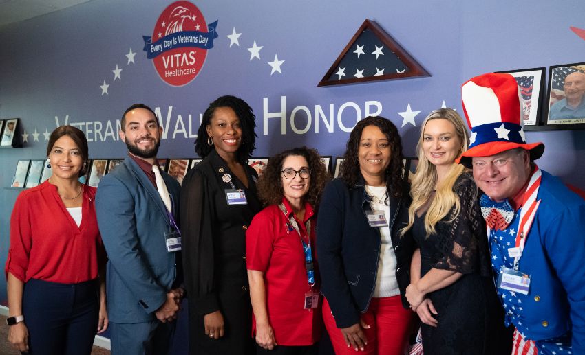 The VITAS team poses in front of the Veterans Wall