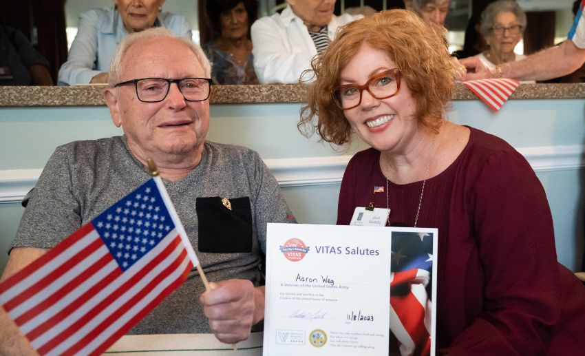 A veteran holds an American flag and a certificate of appreciation