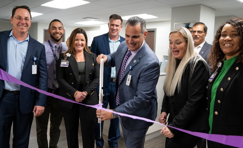 Oversized scissors are used to cut the ceremonial purple ribbon