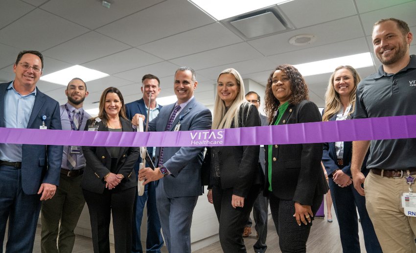 VITAS Healthcare and Broward Health representatives pose behind a ceremonial purple ribbon