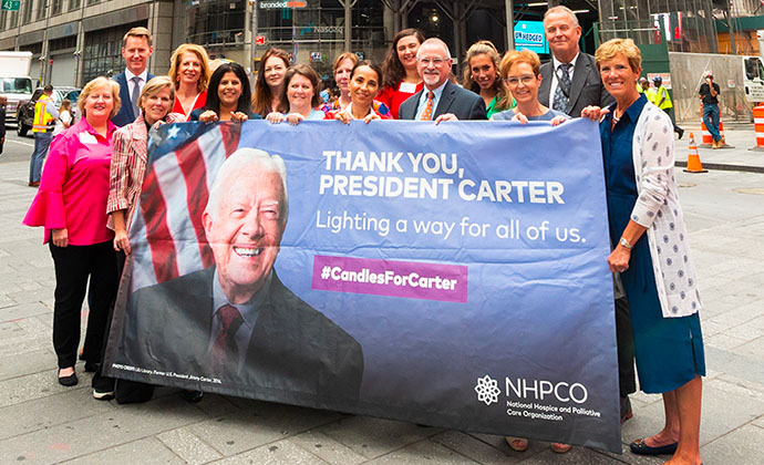 A group of hospice leaders hold a banner that says, 