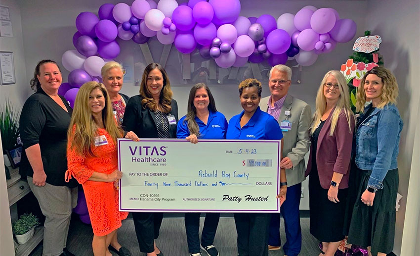 A group poses in front of the VITAS logo with a ceremonial oversized check.
