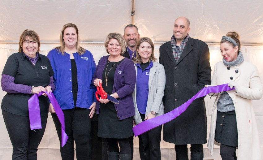 The group poses for the ceremonial ribbon cutting with a purple ribbon