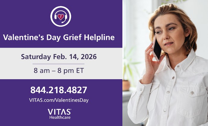 A woman talks on a phone with information displayed about the Valentine Helpline on screen next to her