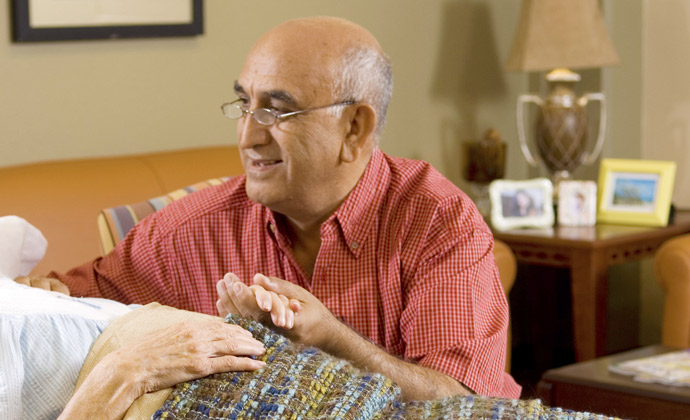 Un hombre sostiene la mano de su esposa mientras ella yace en una cama de hospital