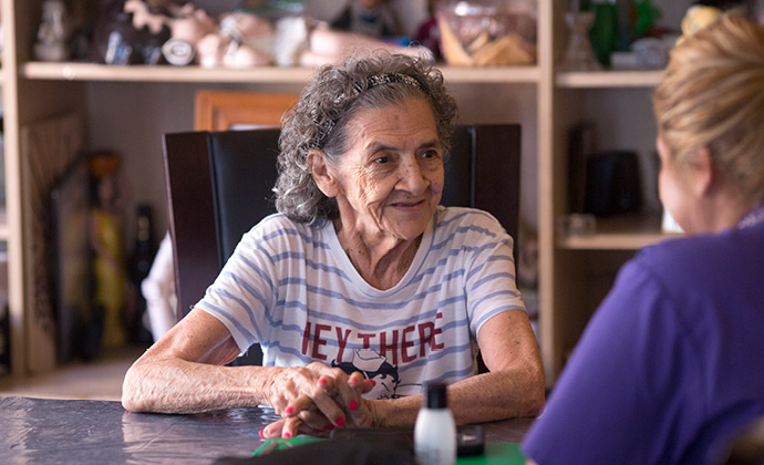 Una paciente y una enfermera de VITAS hablan sentadas en una mesa de la cocina