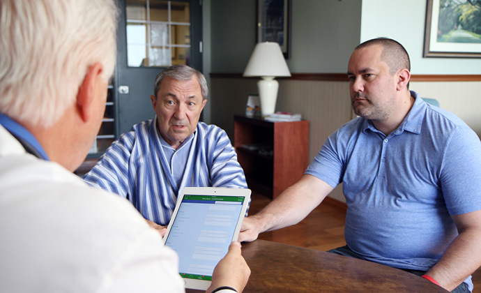 Dos hombres sentados a la mesa hablan con un médico de VITAS