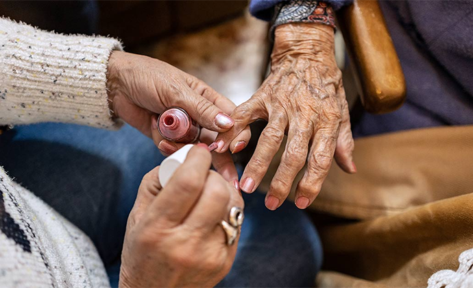 An elderly woman receives a manicure.