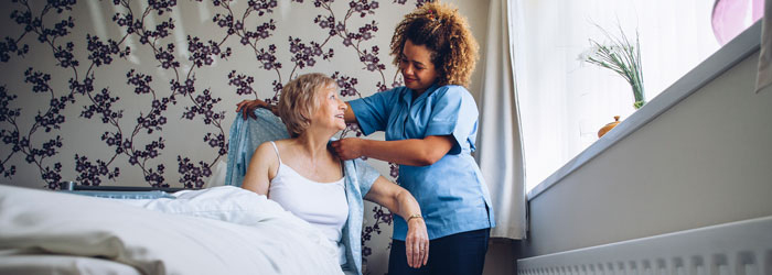 Hospice aide helping patient get dressed