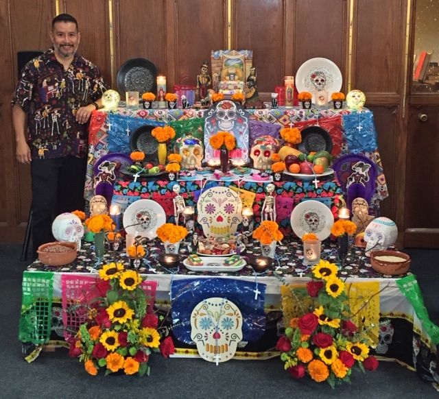 Alex next to an altar created for Dia de los Muertos