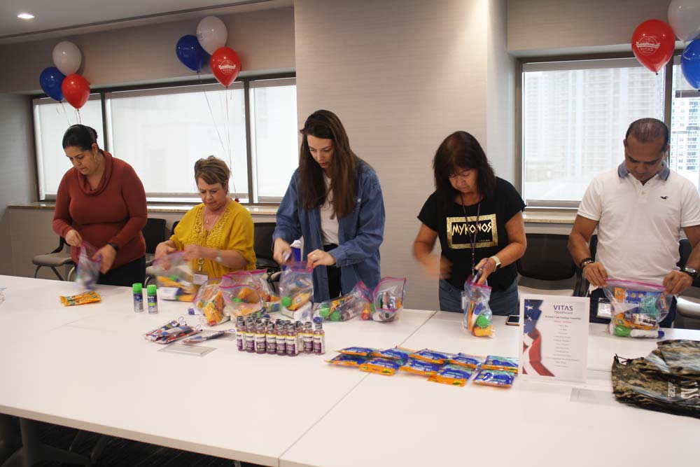 An assembly line of VITAS employees puts shaving cream, Listerine and other personal care items into the care packages