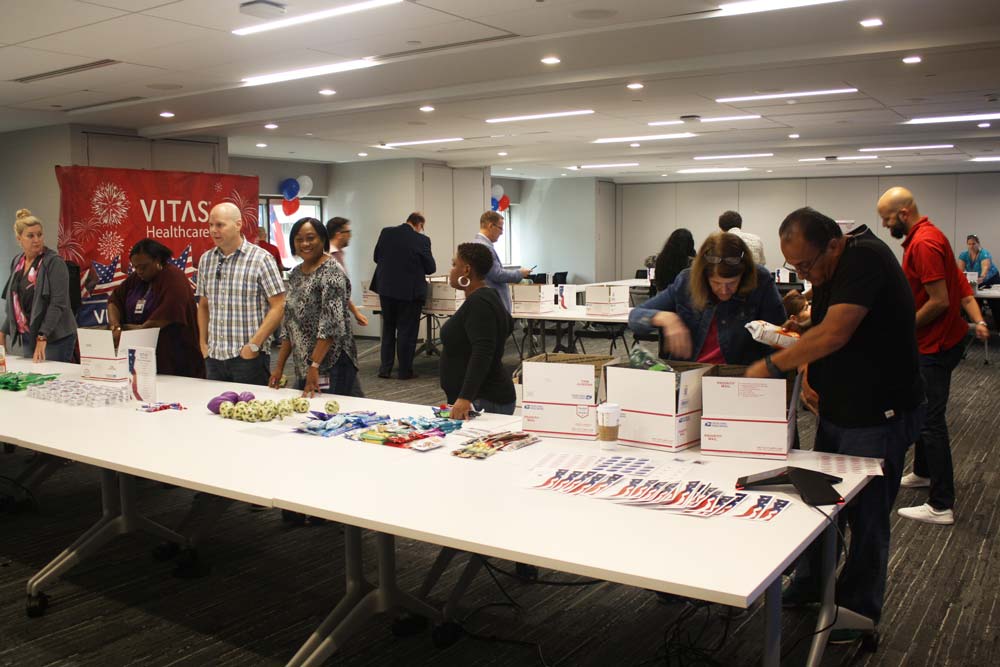 A long conference-room table with items set up to put into care packages