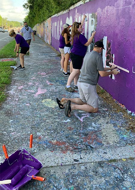 The team first paints a base coat of VITAS purple over the expanse of wall