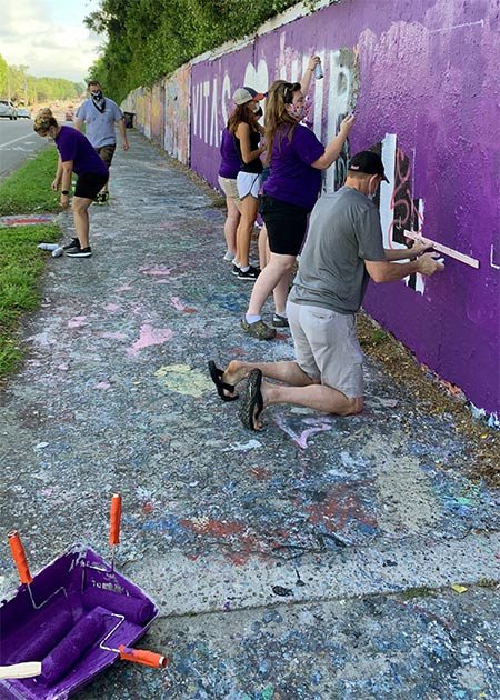 The team first paints a base coat of VITAS purple over the expanse of wall