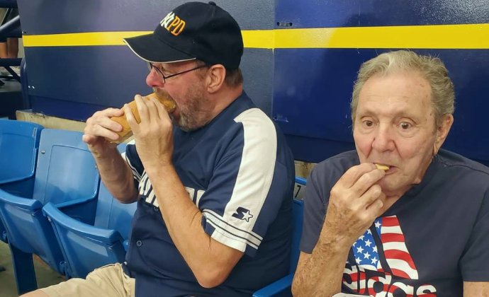 VITAS patient Frank Vela enjoys a snack at the ballpark with his longtime friend