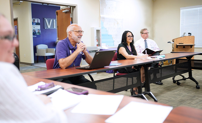 VITAS care team members talk and smile at a table in a conference room